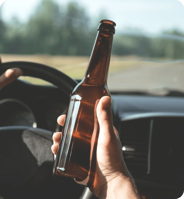 a car driver holding a bottle containing alcohol