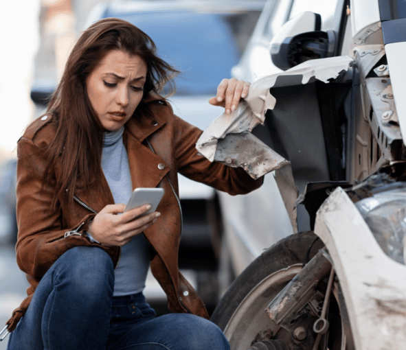 woman kneeling next to car after crash