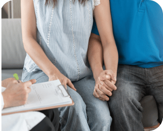 man and woman holding hands and speaking to a physician