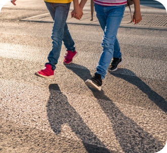the legs of two boys crossing the road